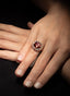 Close-up of emerald and diamond ring on model's hand, showcasing fine craftsmanship.