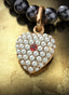 Heart’s Desire Medallion with gold bail on a pearl necklace, elegantly displayed on a table.