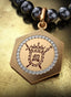 4:14 Medallion with gold hinge connector on a pearl necklace, elegantly displayed on a table.