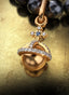 Power & Dominion Medallion with gold connector on a pearl necklace, elegantly displayed on a table.