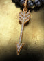 Secret Weapon Medallion with gold connector on a pearl necklace, elegantly displayed on a table.