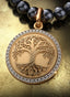 Roots & Branches Medallion with gold connector on a pearl necklace, elegantly displayed on a table.