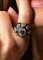 Model wearing an aquamarine, emerald, and diamond ring, showing its bold design.