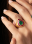 Close-up of emerald and ruby teardrop ring in 18K yellow gold, showcasing fine craftsmanship.