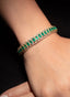 Emerald and diamond cuff bracelet in 18K yellow gold, showcasing its beautiful design and gemstones.