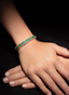Model wearing an emerald and diamond cuff bracelet, highlighting its elegant size and proportions.