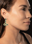 Model wearing emerald and diamond earrings, highlighting their size and unique design. 