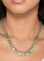 Close-up of emerald fringe necklace on model's neck, showcasing its elegant drape.