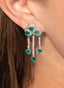 Close-up of 5.5 carat heart-shaped emerald and diamond earrings in 14K white gold on model.