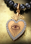 The Revelation Medallion with gold connector on a pearl necklace, elegantly displayed on a table.