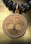 Roots & Branches Medallion with gold connector on a pearl necklace, elegantly displayed on a table.