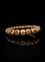 Gold Cross of Faith bracelet, laying flat on a black surface.