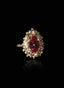 Close-up of rubellite and diamond ring on black background, highlighting gemstone brilliance.