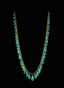 Close-up of emerald fringe necklace on a black background, highlighting gemstone beauty.