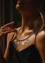 Woman wearing Inspocco pearl necklace with Inspocco medallions, against a dark background